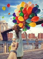 Девушка с облаком воздушных шаров под мостом